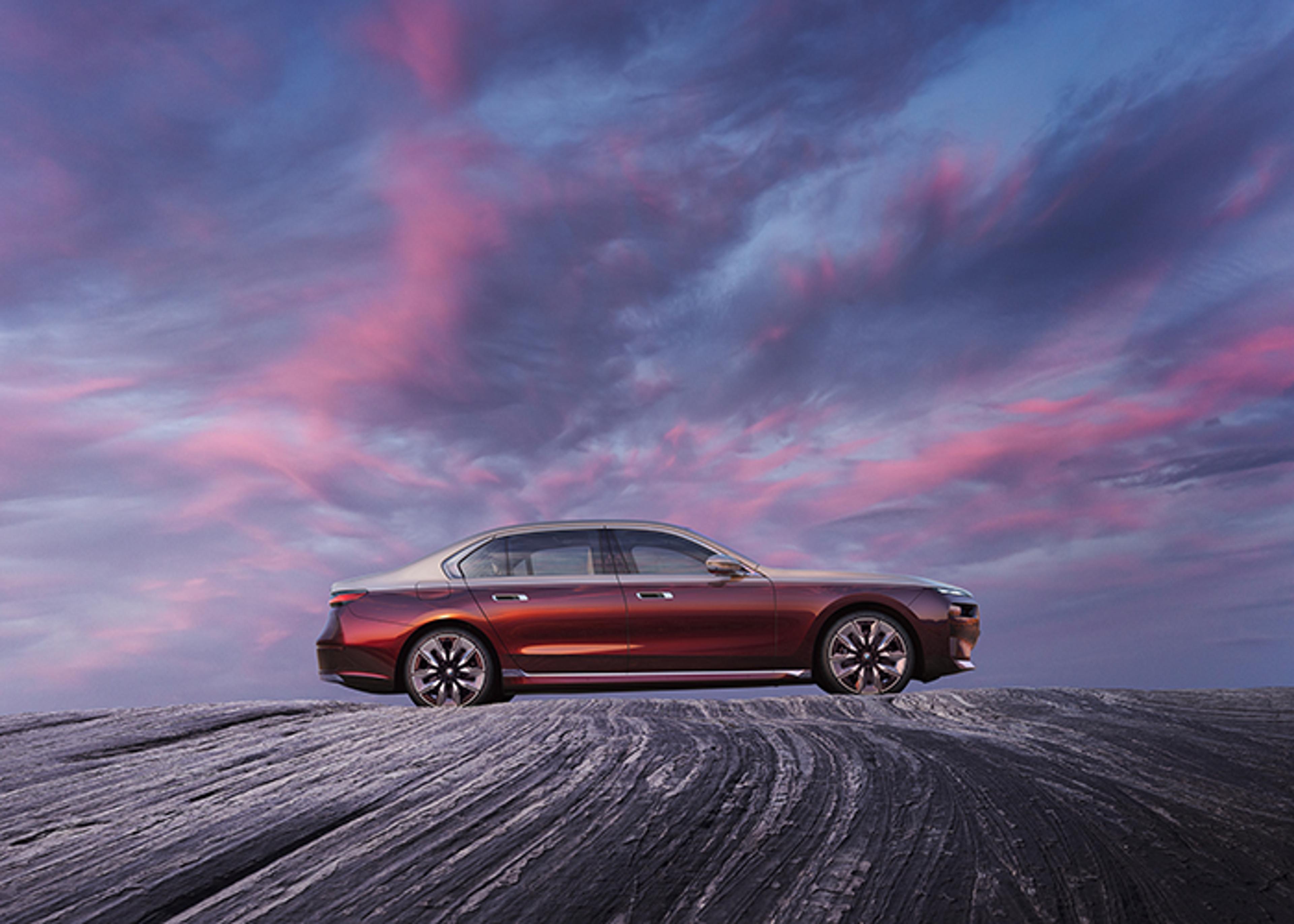 Maroon and tan BMW parked on cracked stone surface reflecting pink-violet cloudy sky.