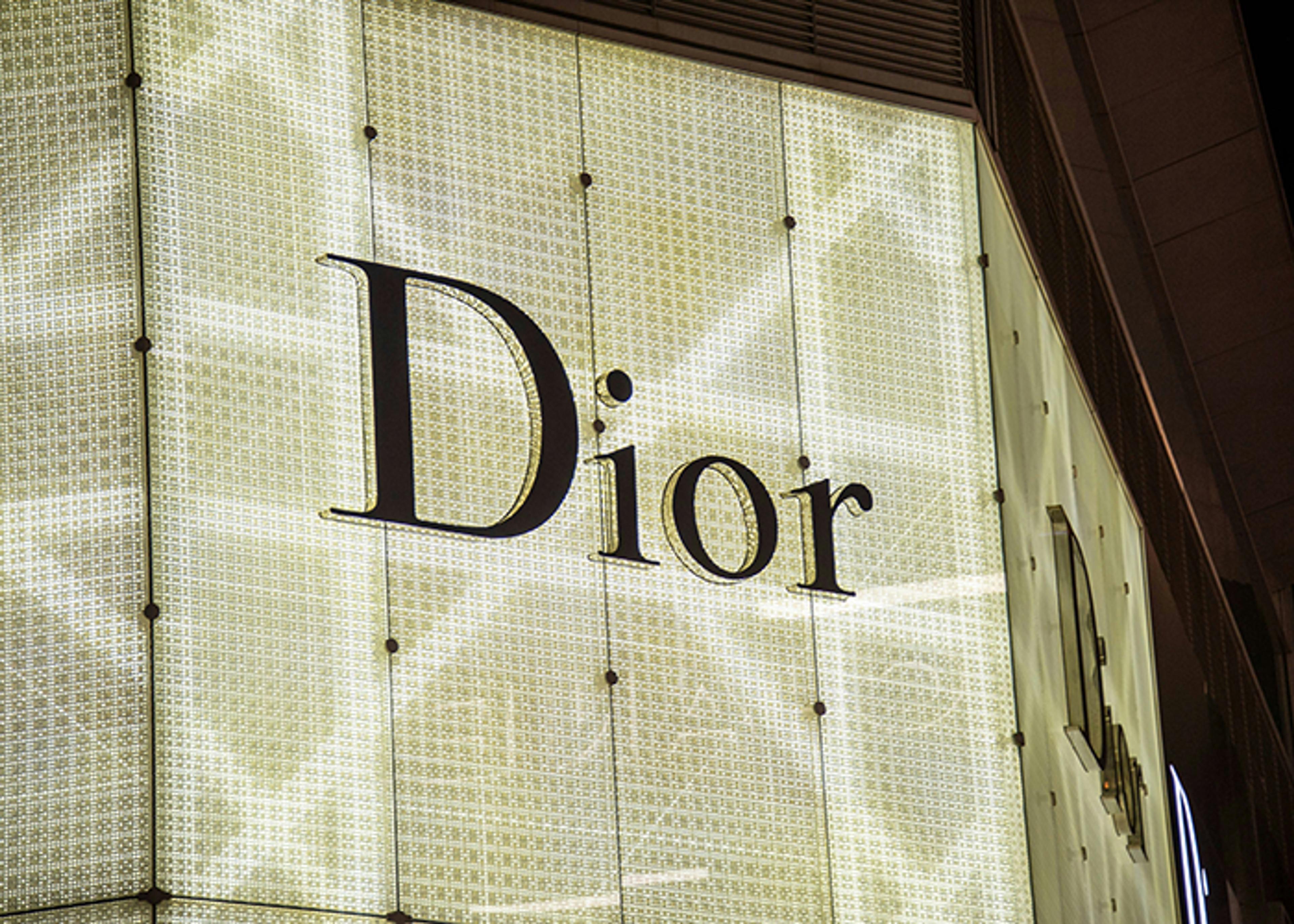 Illuminated Dior logo on a textured facade.