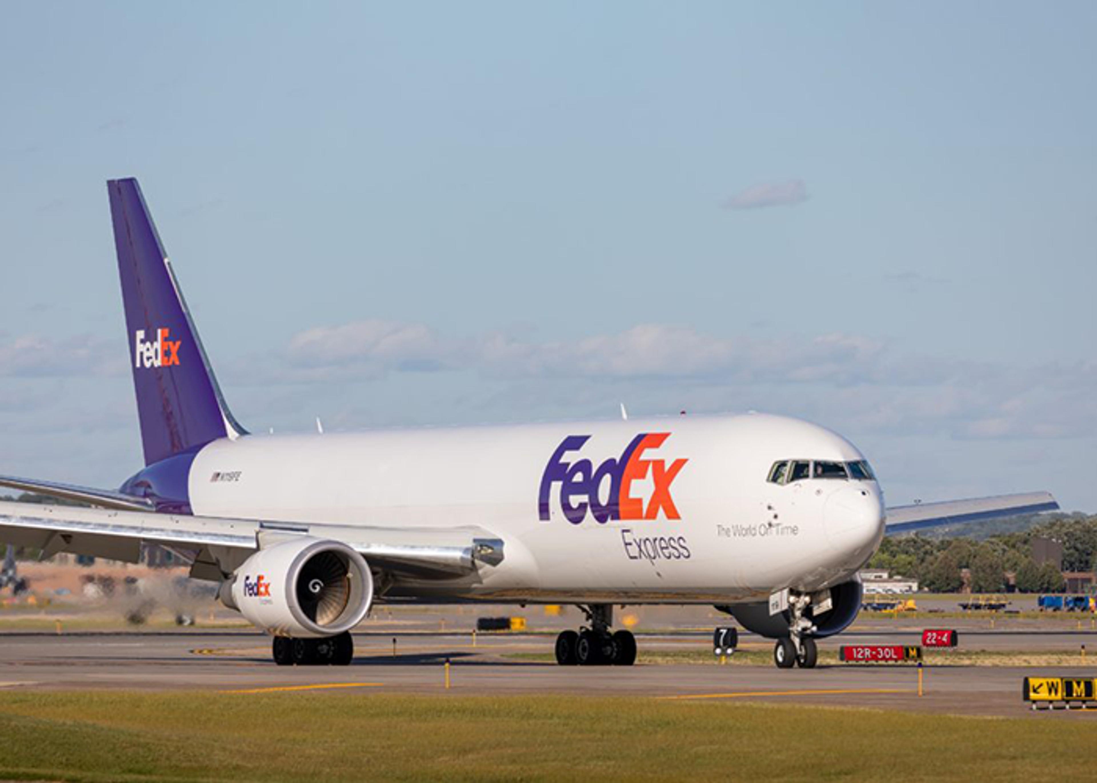 A FedEx cargo airplane on a runway is viewed at eye level.