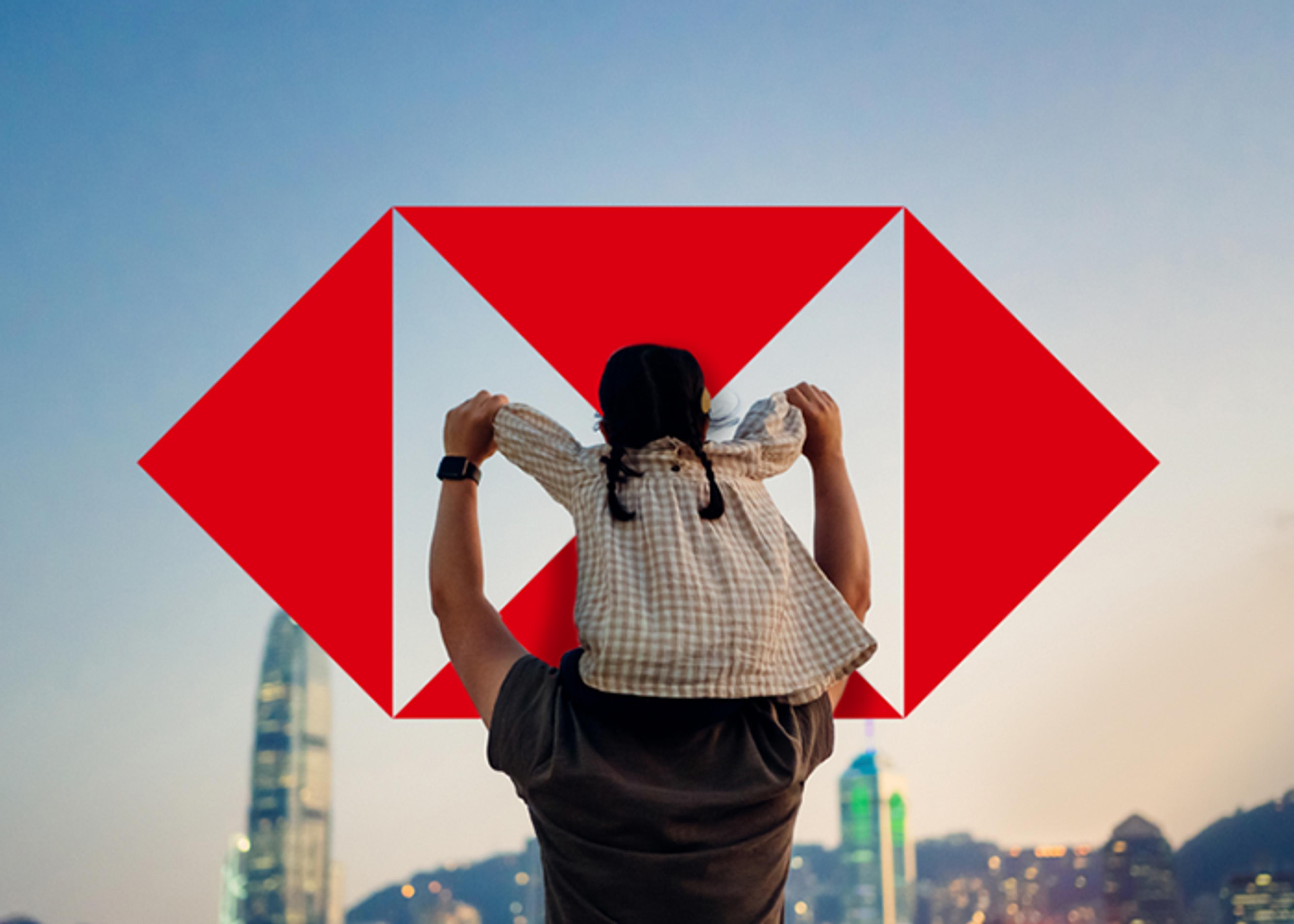 A man with a child on his shoulders, viewed from the back, with the HSBC symbol in the background against a cityscape.