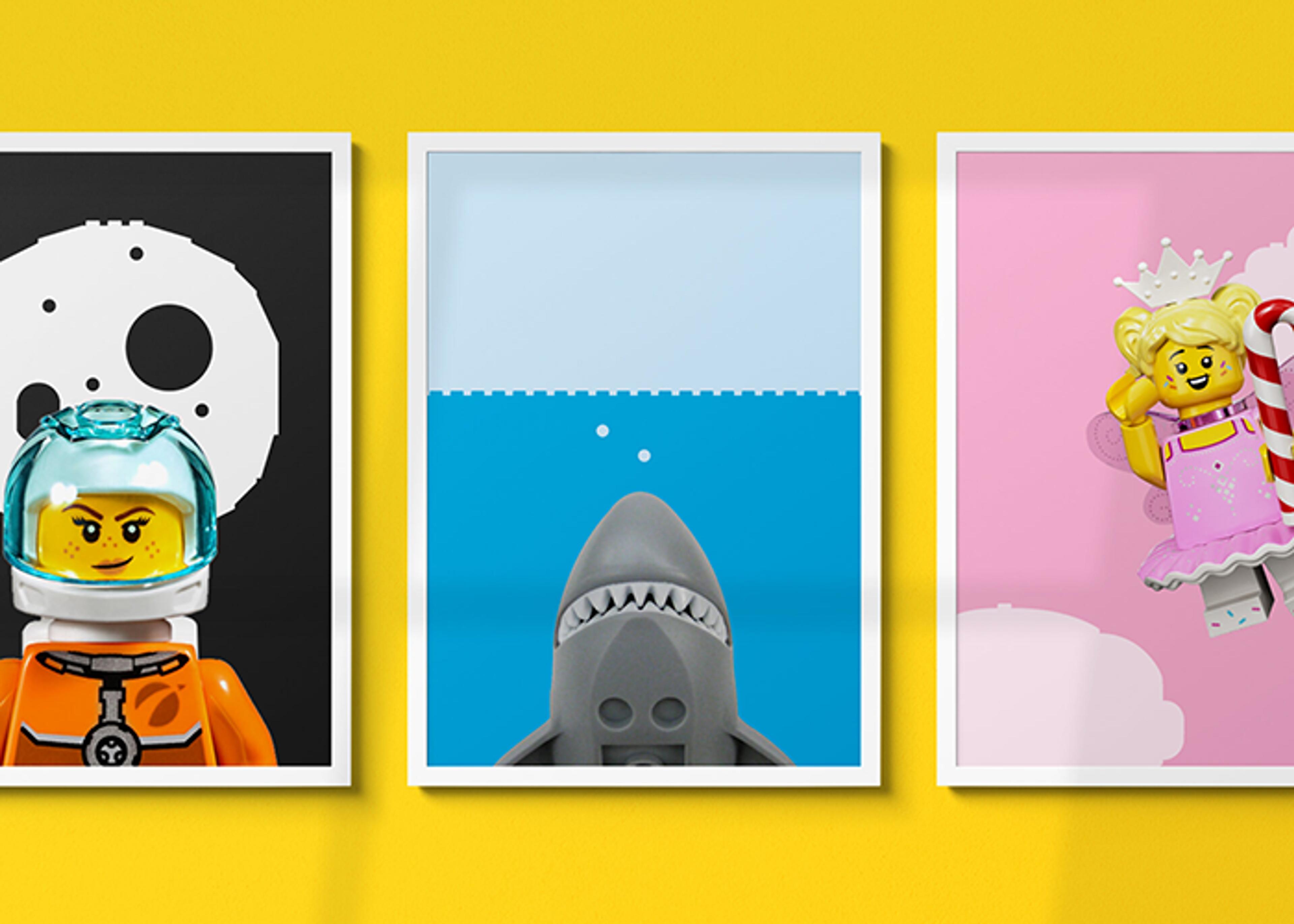 Three framed LEGO art prints against a yellow wall depict a LEGO astronaut against a moon background, a LEGO shark in water, and a LEGO princess with a smiling expression and candy cane.