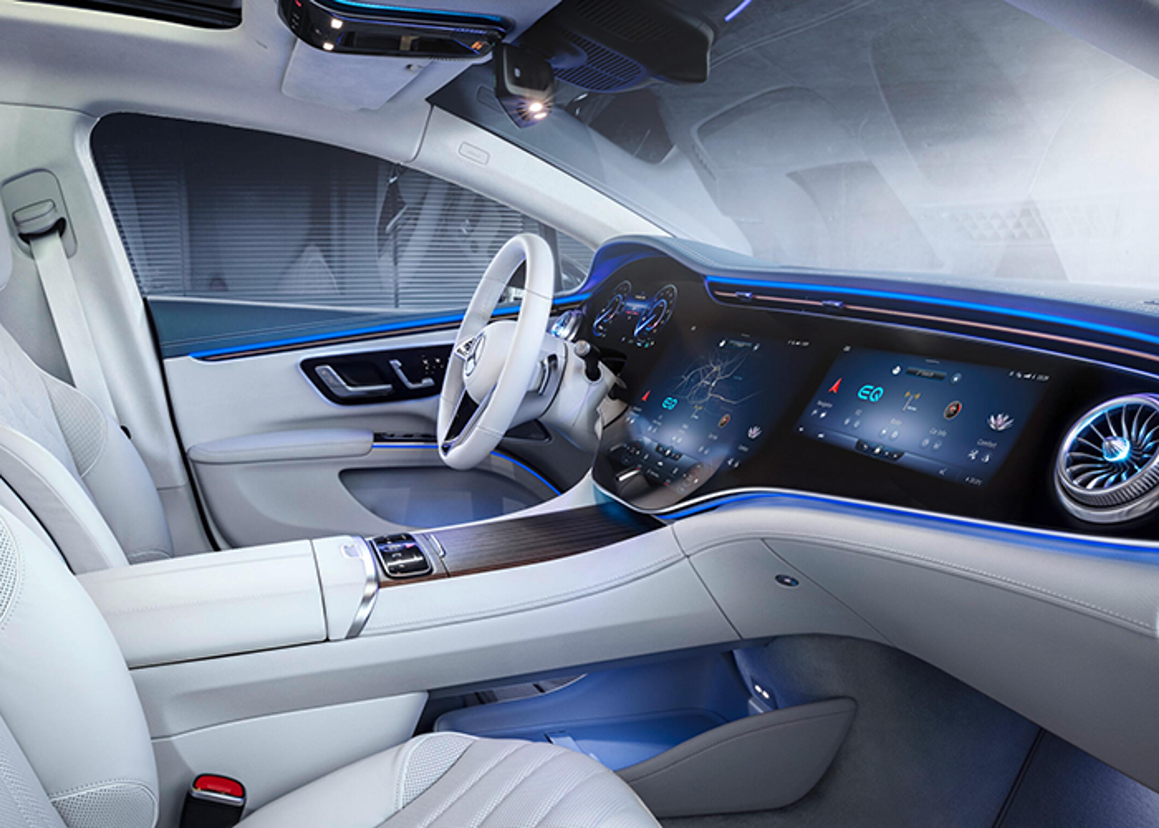 Interior view of a Mercedes-Benz, featuring white premium upholstery, steering wheel, and a digital dashboard extending across the vehicle's width, accented by ambient blue lighting.