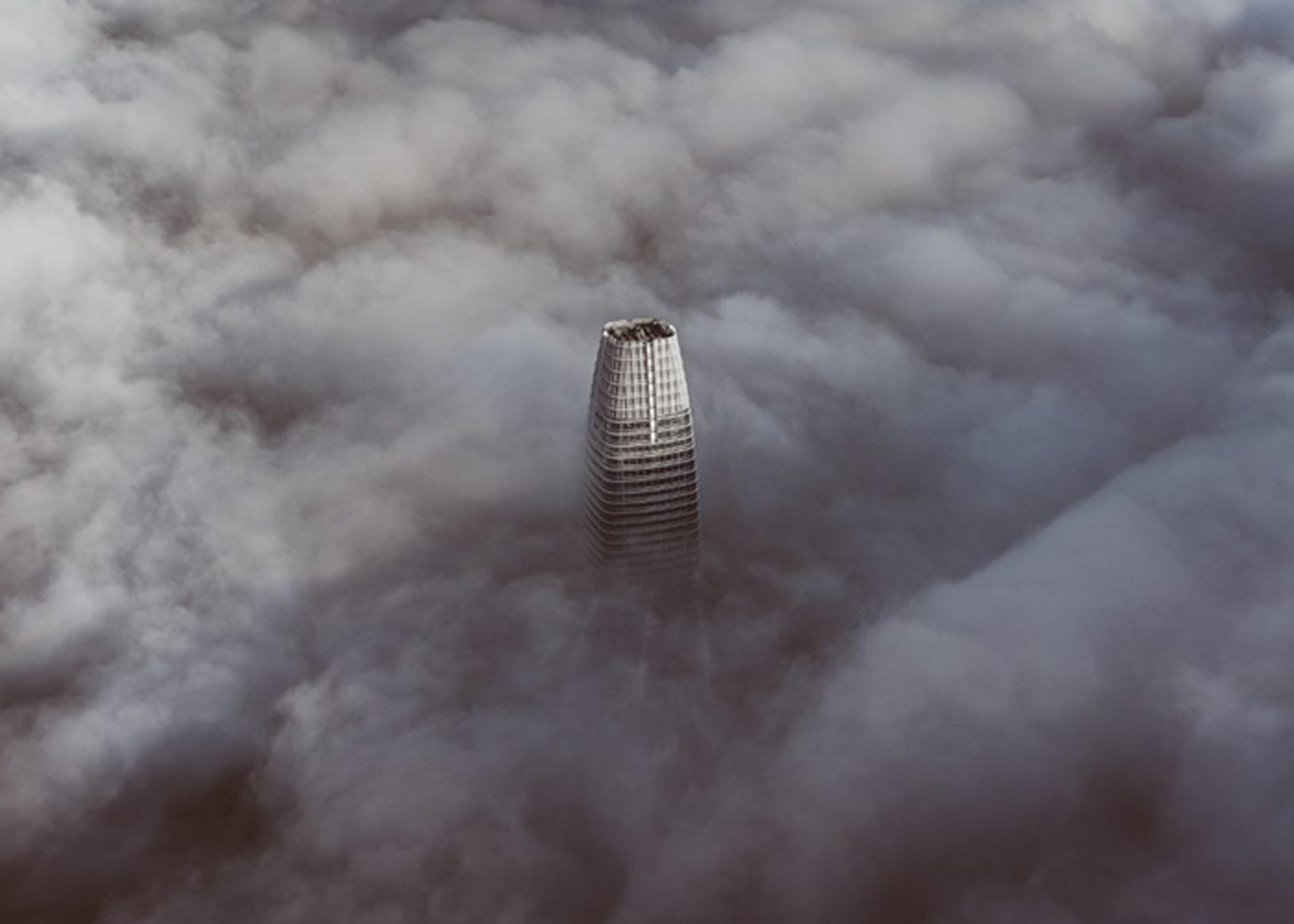 Aerial view of a skyscraper rising above a dense fog bank.