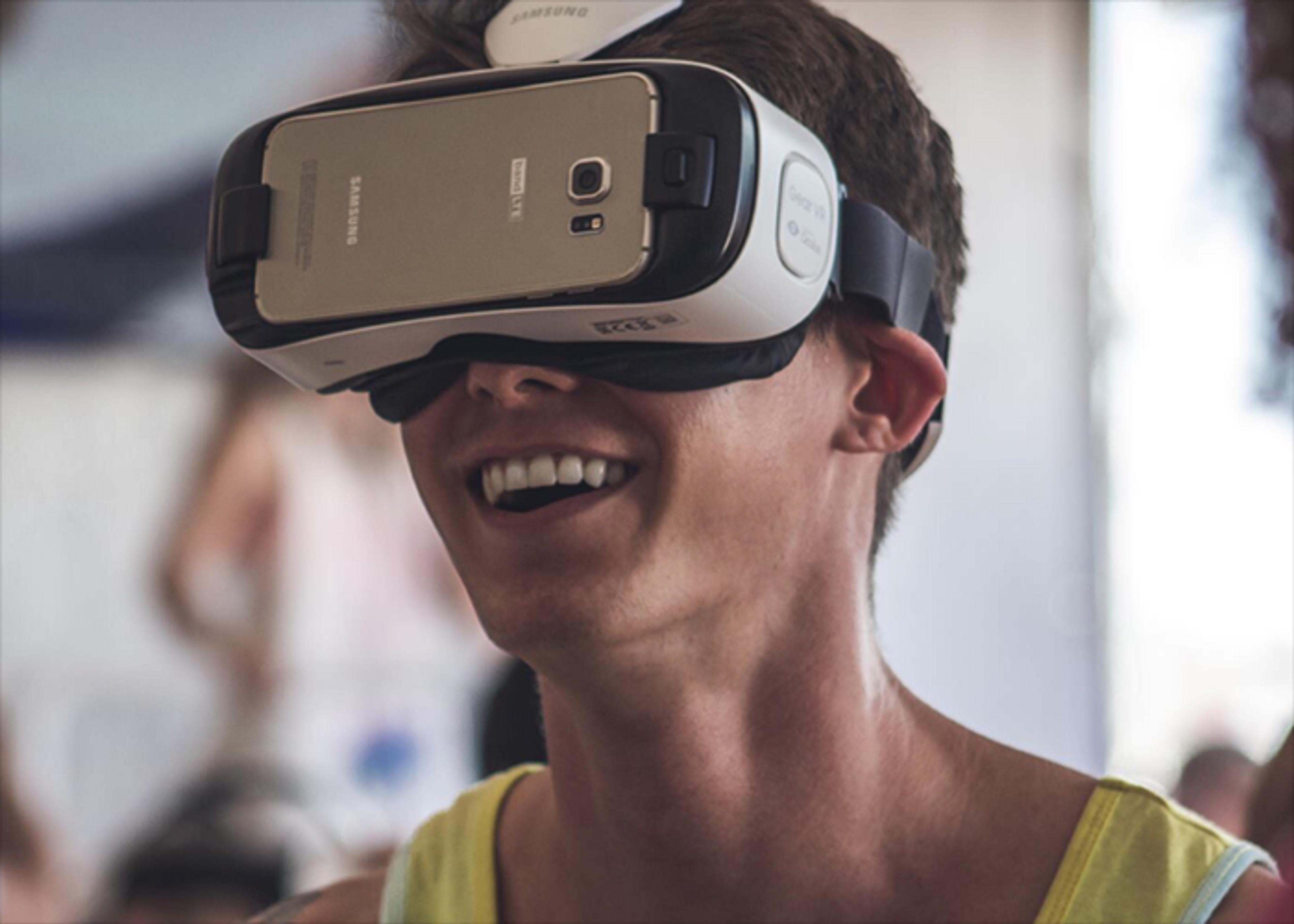Individual wearing a Samsung VR headset, expressing a wide smile.