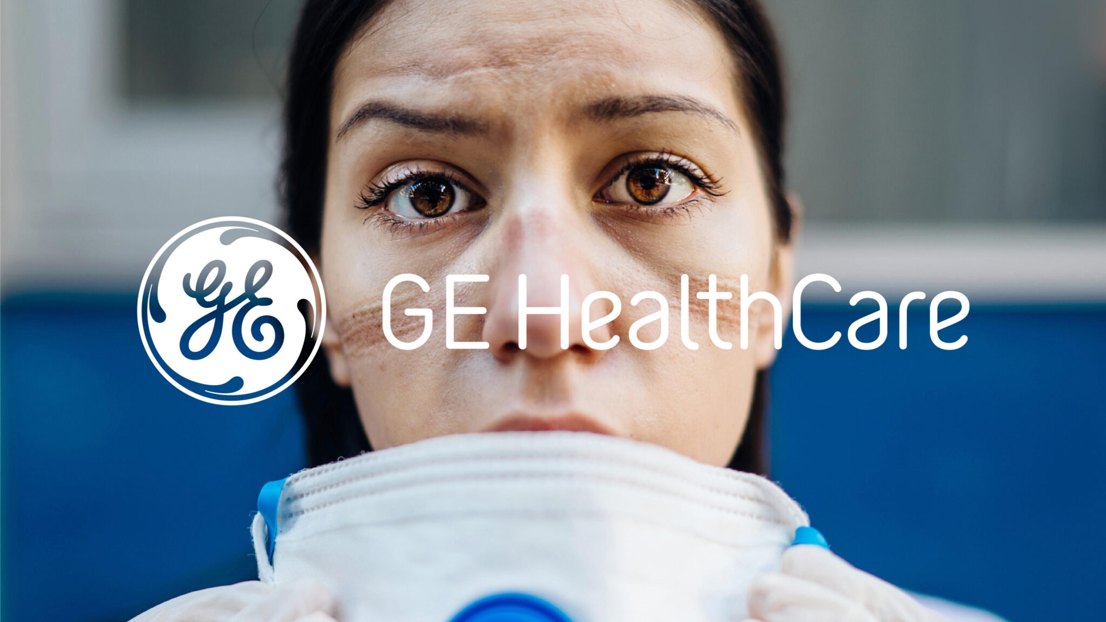 Close-up of a health worker with visible marks on their face, wearing a mask with the GE HealthCare logo overlayed. Their expression appears serious and determined.