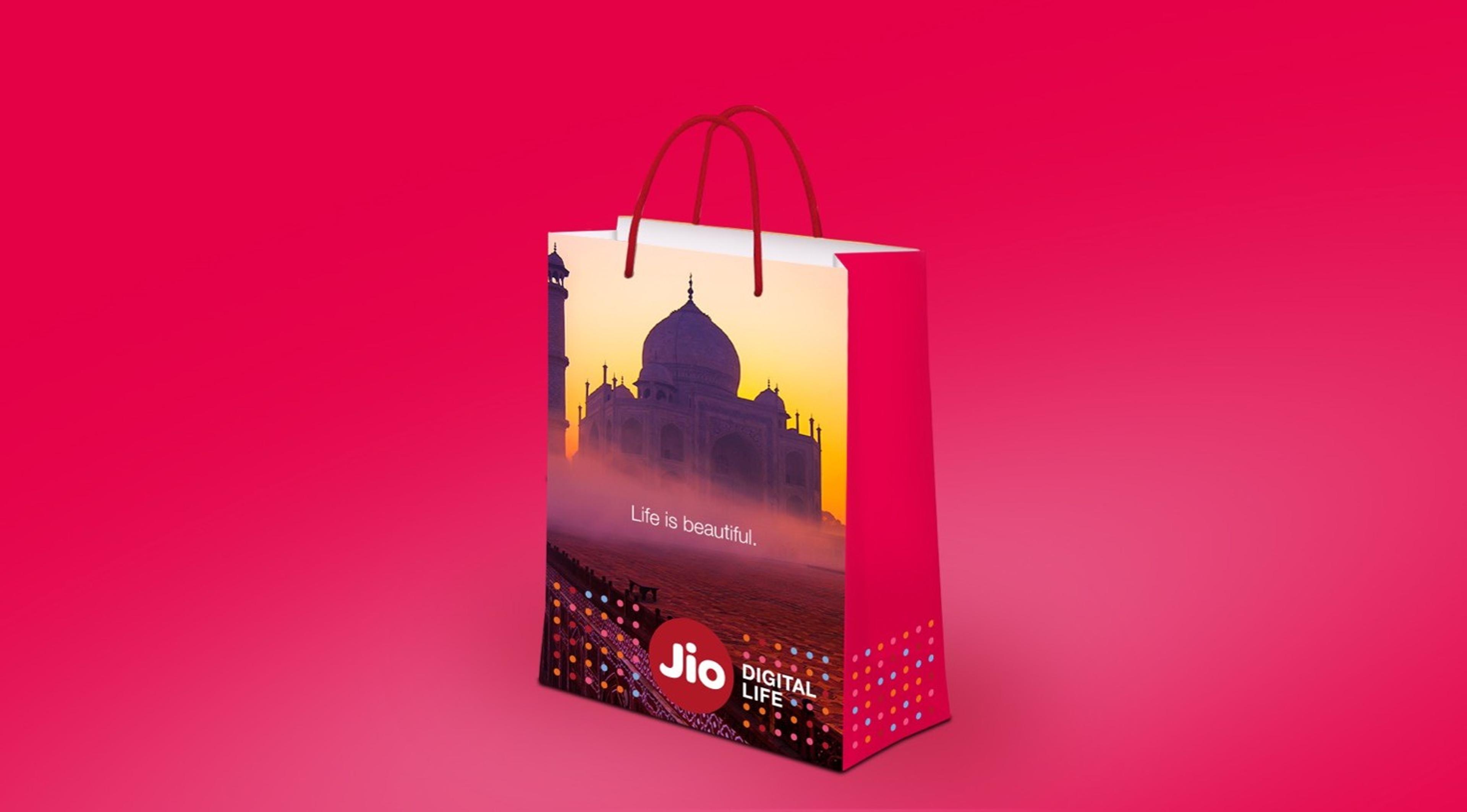 Promotional shopping bag with red handles, against a red background, features an image of the Taj Mahal and branding for Jio Digital Life.