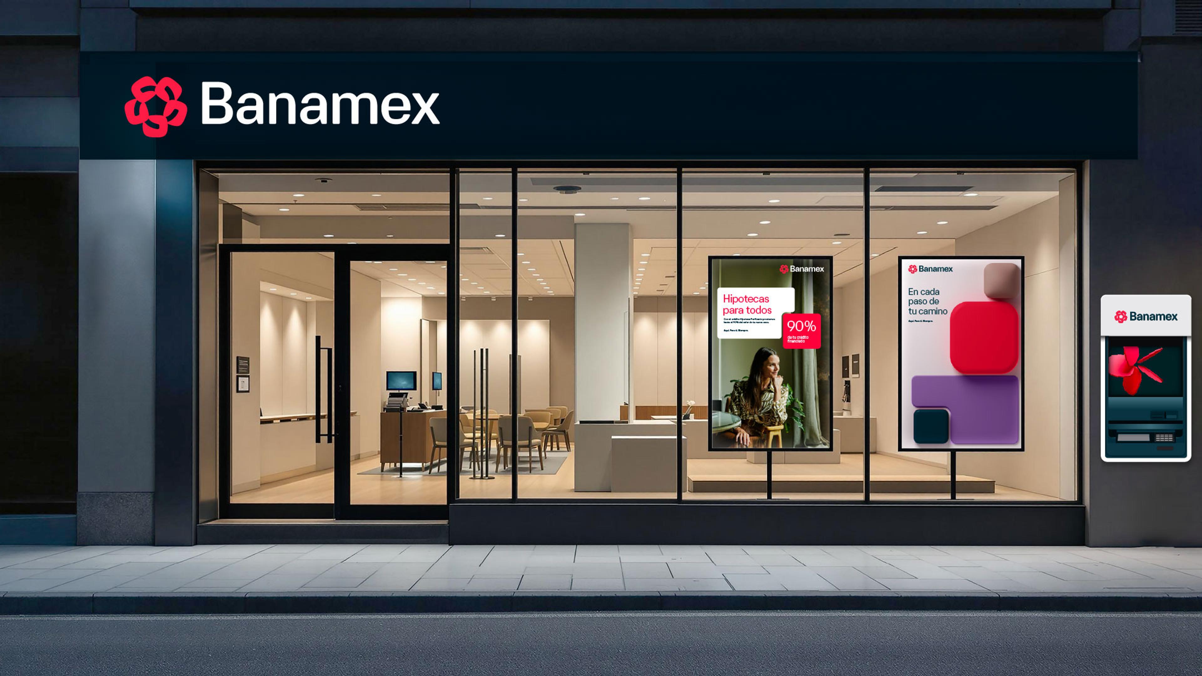 The exterior of a Banamex bank branch, with large glass windows displaying interior furniture and illuminated promotional posters, including mortgage offers and abstract shapes. An ATM is mounted on the wall to the right of the entrance.