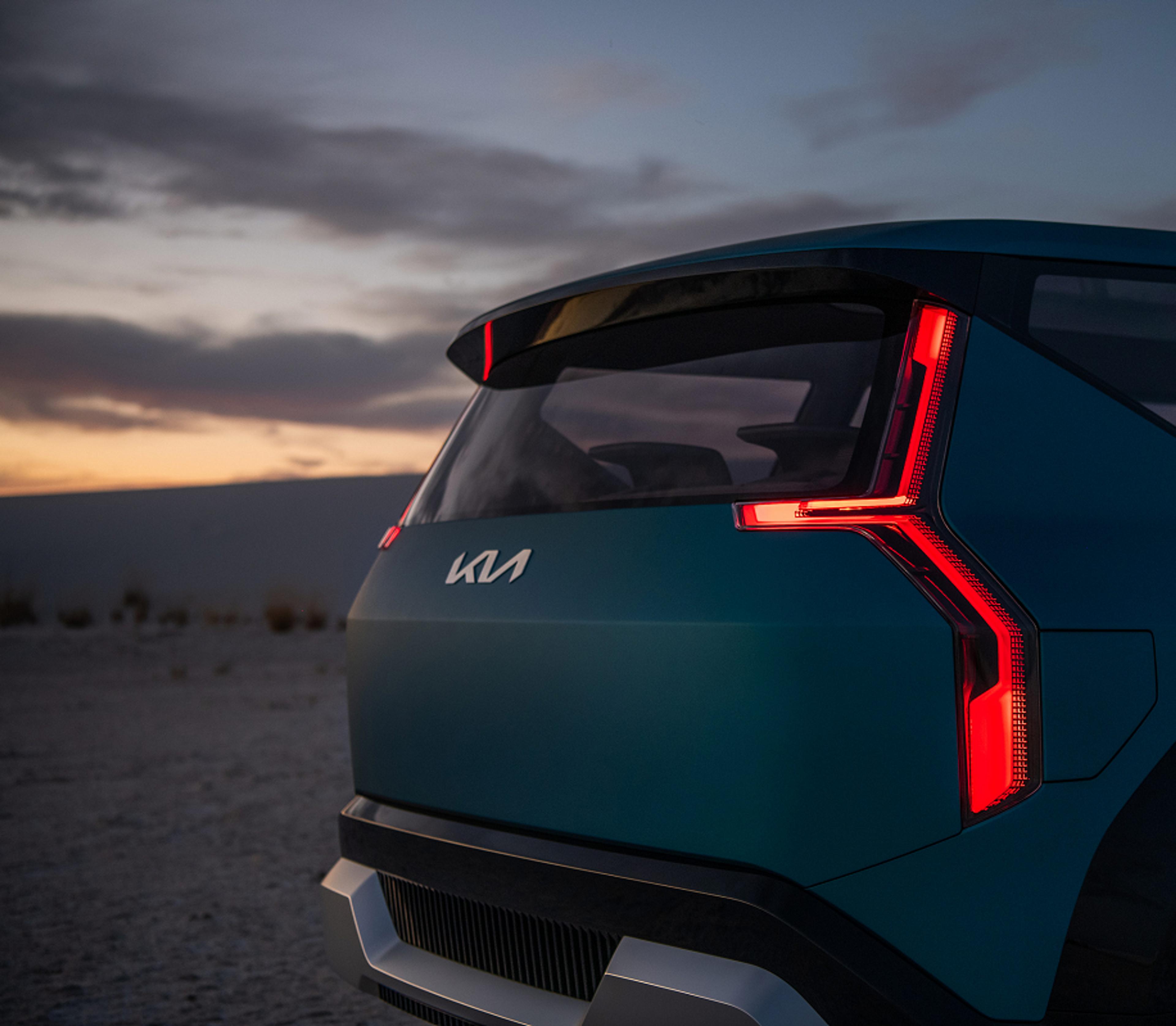 Close-up on the rear of a teal Kia SUV, featuring distinctive vertical brake lights in a desert setting.